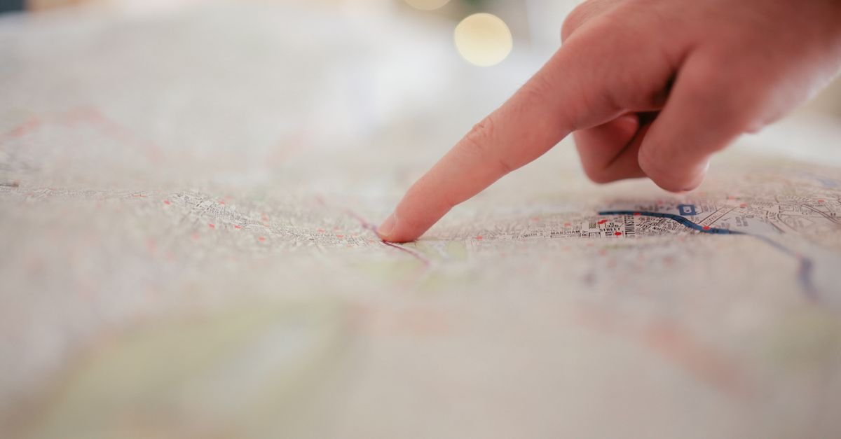Main pointant un plan d'urbanisme dépliée sur une table de travail