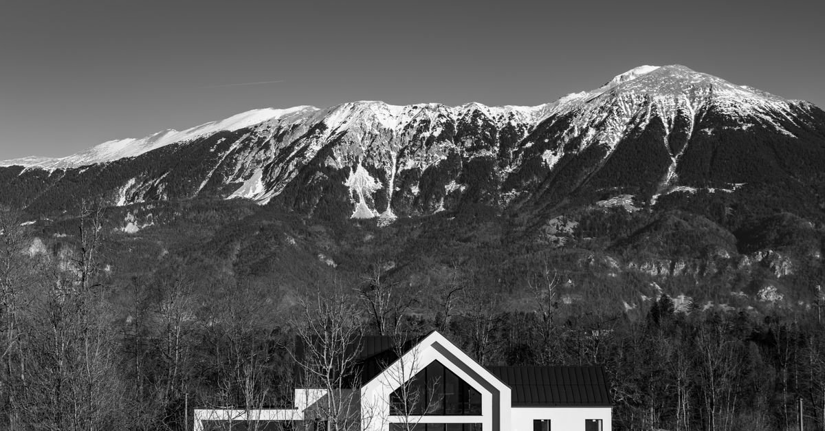 Maison contemporaine aux lignes sobres implantée devant un massif montagneux