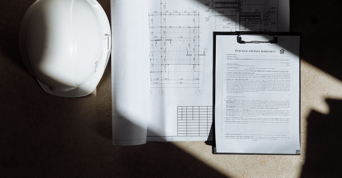Feuilles de plans d'architecte et document contractuel posés sur une table