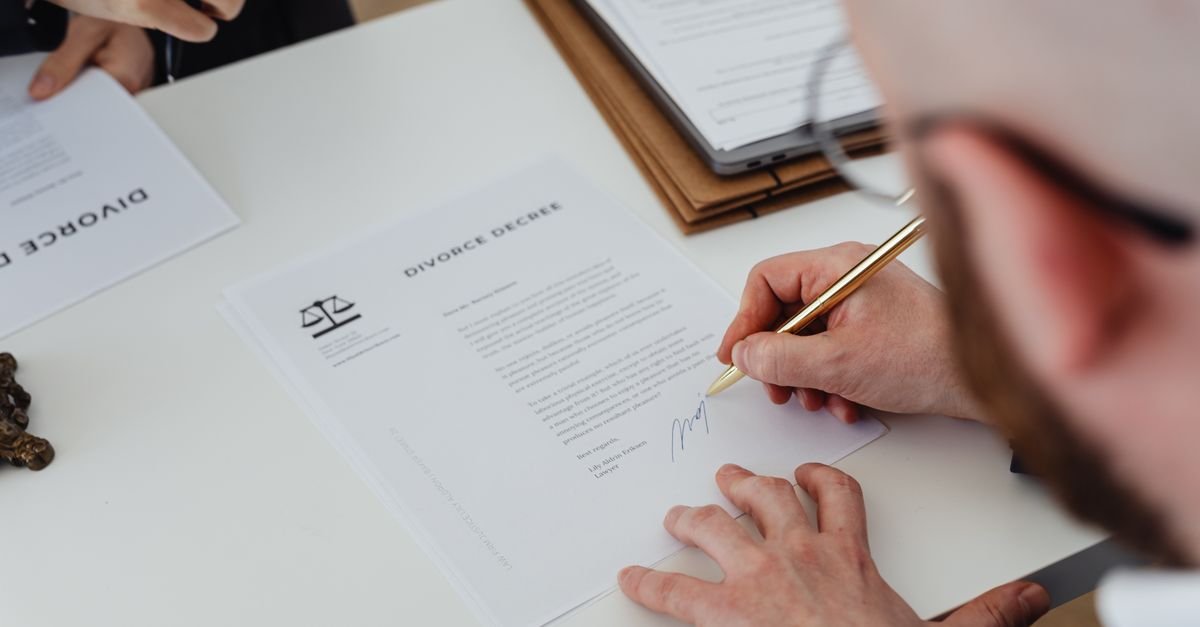 Personne signant des documents administratifs sur une table en bois