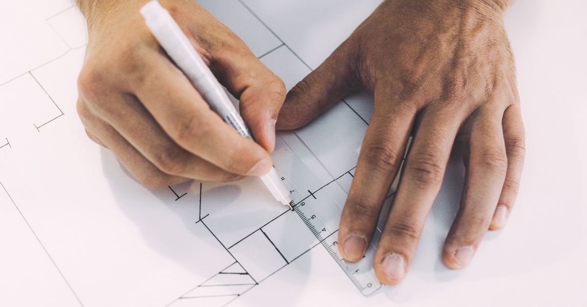 Personne dessinant des plans avec une règle et un crayon